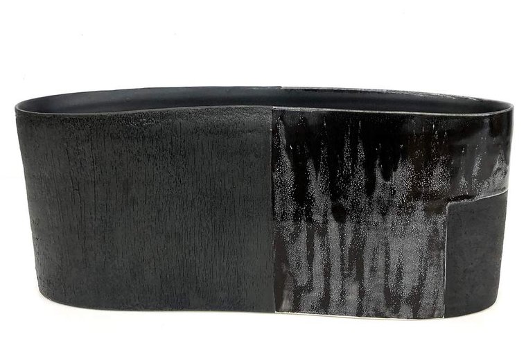 Soot Vessel by Kathy Erteman is a black porcelain vessel with a section of black texture slip and a contrasting gloss black glaze on the wheel thrown and altered by the ceramic artist, who’s represented by Hostler Burrows Gallery