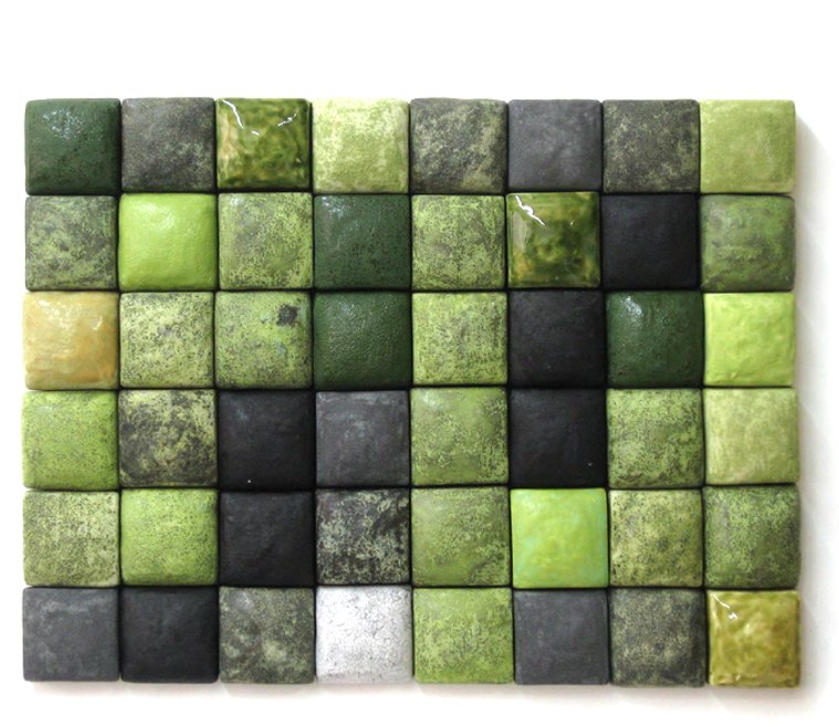 Two-inch ceramic squares make up the architectural installation titled Seafoam Composition by Kathy Erteman. The slip-cast squares have a textured glaze in an array of greens, grays and black. The individual squares are mounted on wood panels