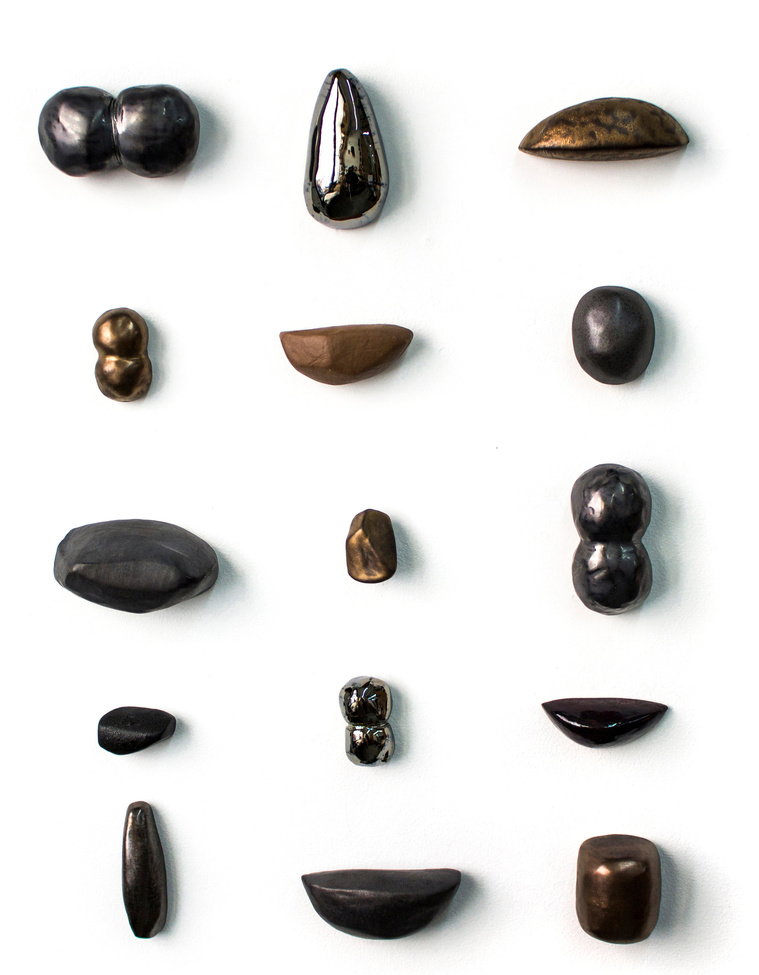 By artist Kathy Erteman, Curio Cabinet is a ceramic wall sculpture with porcelain sculpted forms based on nature in varying organic shapes. These pods have been glazed in gold, silver, and pewter to unify the elements in the ceramic wall piece