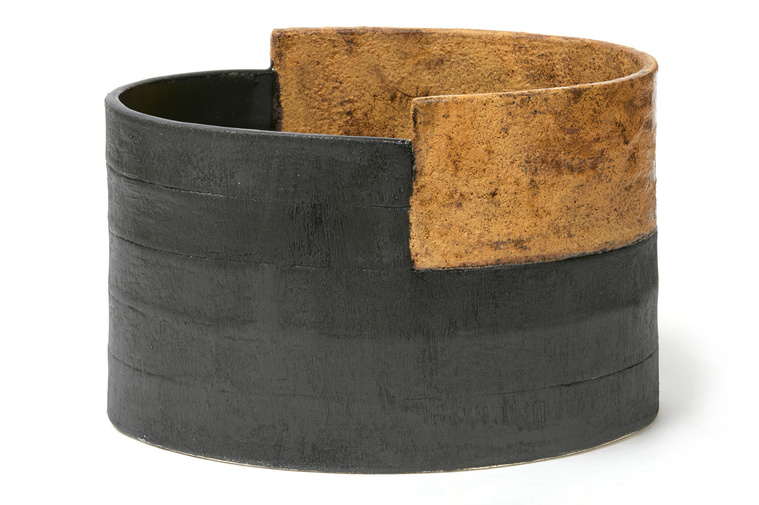 The Titanium Ledge Vessel is a hand-built stoneware oval vessel with an irregular inset top, a titanium rough texture glaze and an inset black glaze. Like many of Kathy Erteman’s pieces, this is a contemporary ceramic vessel
