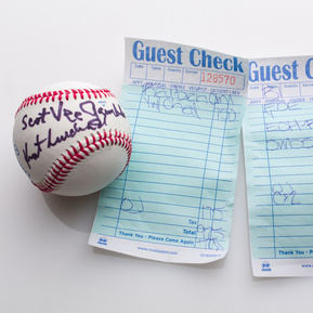 photograph of ephemera from douglas rosenberg's relational performance, containing a baseball signed by all participants in the performance and the bill for the breakfast