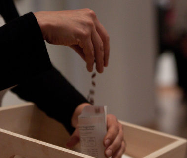 photographs from douglas rosenberg's relational performance art work forgiveness, showing white envelopes from the performance being filled with hyacinth seeds by participants in the gallery