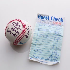 photograph of ephemera from douglas rosenberg's relational performance, containing a baseball signed by all participants in the performance and the bill for the breakfast