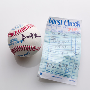 photograph of ephemera from douglas rosenberg's relational performance, containing a baseball signed by all participants in the performance and the bill for the breakfast