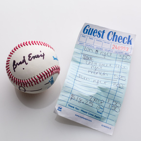 photograph of ephemera from douglas rosenberg's relational performance, containing a baseball signed by all participants in the performance and the bill for the breakfast