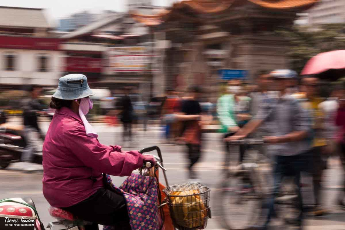 Blurred bicycles wiz past the temple gate in in Kunming, China.