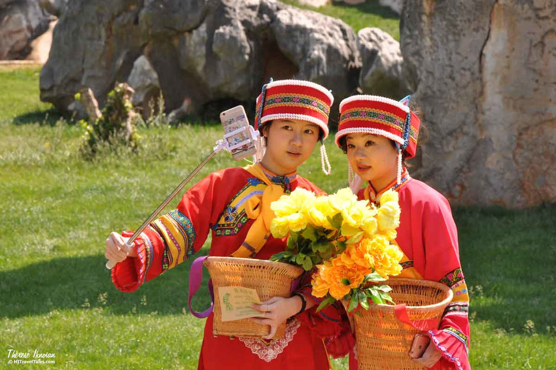 Two colorfully-dressed women taking a selfie in the Stone Forest in Yunnan Province of China. 