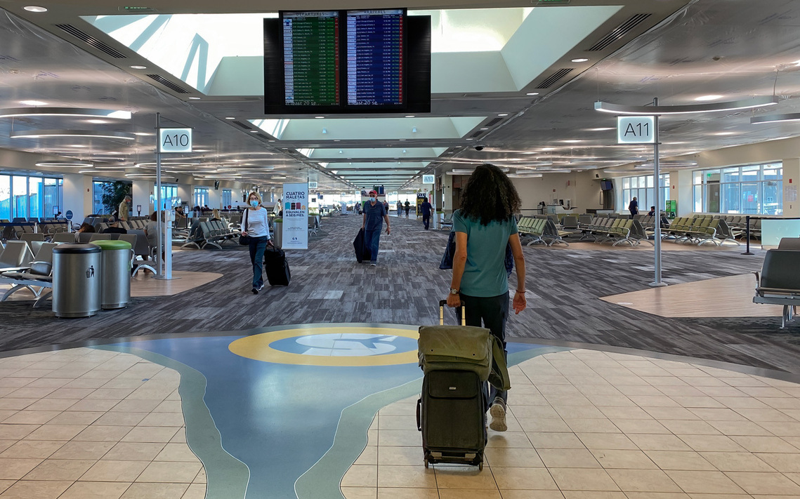 Photo of Therese Iknoian walking through an airport with her camera bags as carryon luggage. 
