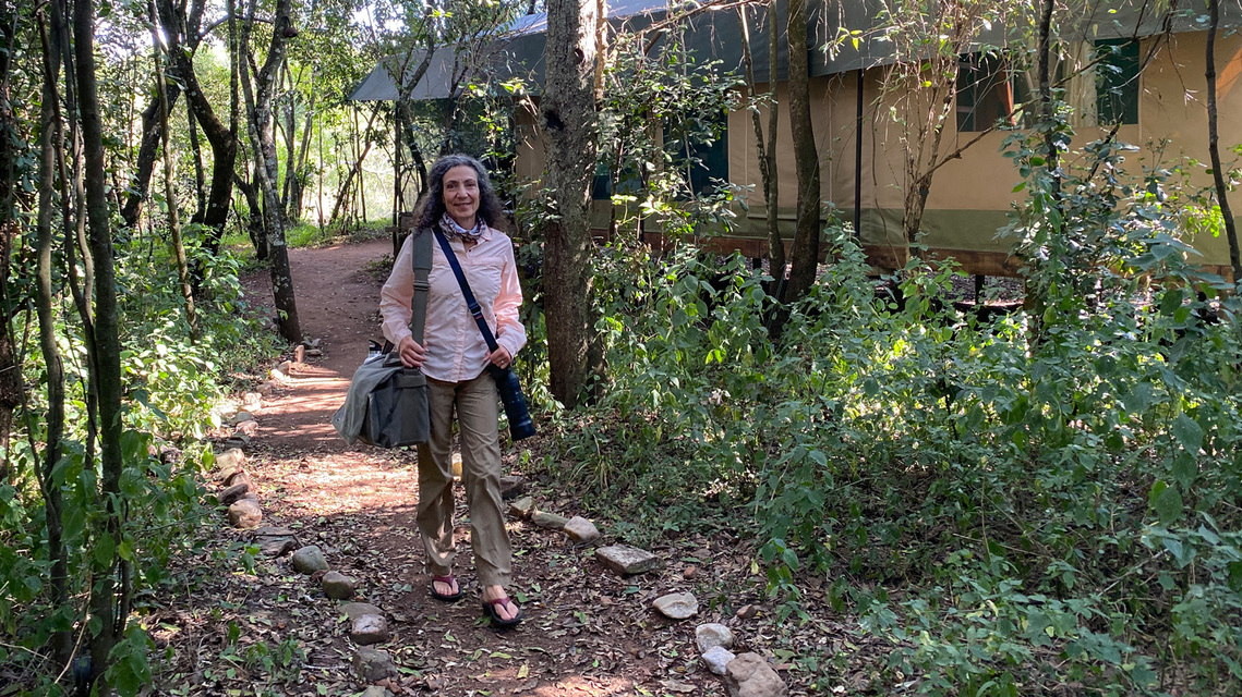 Photo of Therese Iknoian walking to a safari vehicle with camera gear slung over her shoulder