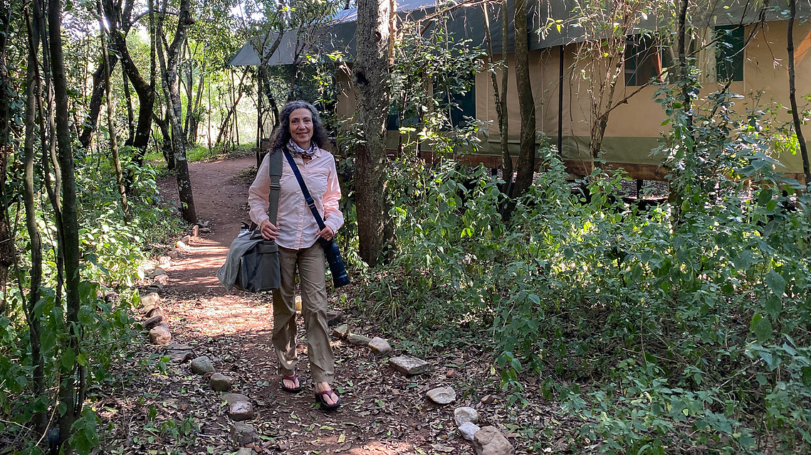 Photo of Therese Iknoian walking to a safari vehicle with camera gear slung over her shoulder