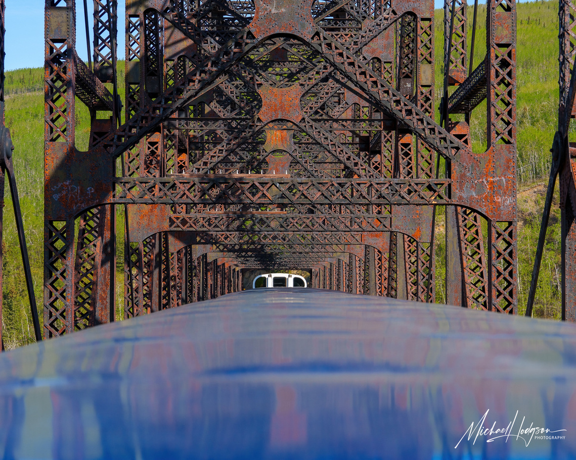 Photo from inside a trestle bridge, shooting over the top of the railcars behind the viewing platform on an Alaska Railroad Denali Star train.