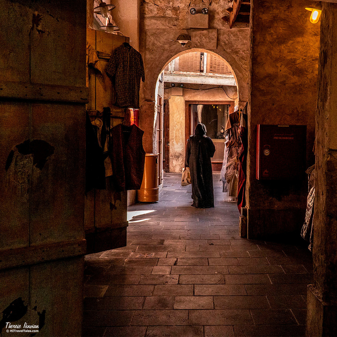 Photo of a woman passing through an arch in the souk in Doha, Qatar -- after photo processing. 