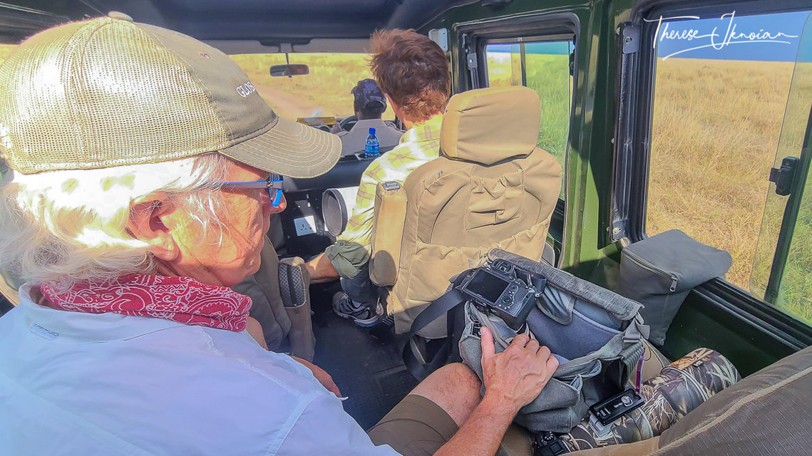 Photo of Michael Hodgson with his camera gear beside him inside a safari vehicle on a photo safari in Kenya. 
