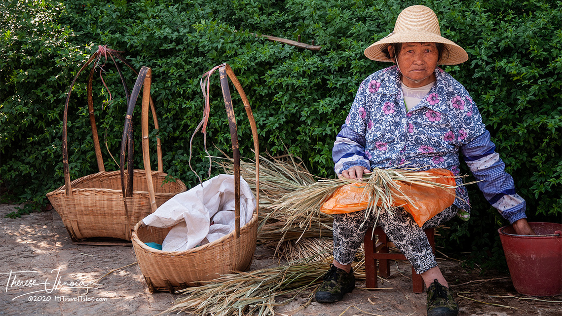 A woman with baskets and dry grasses in Kunming, China. 