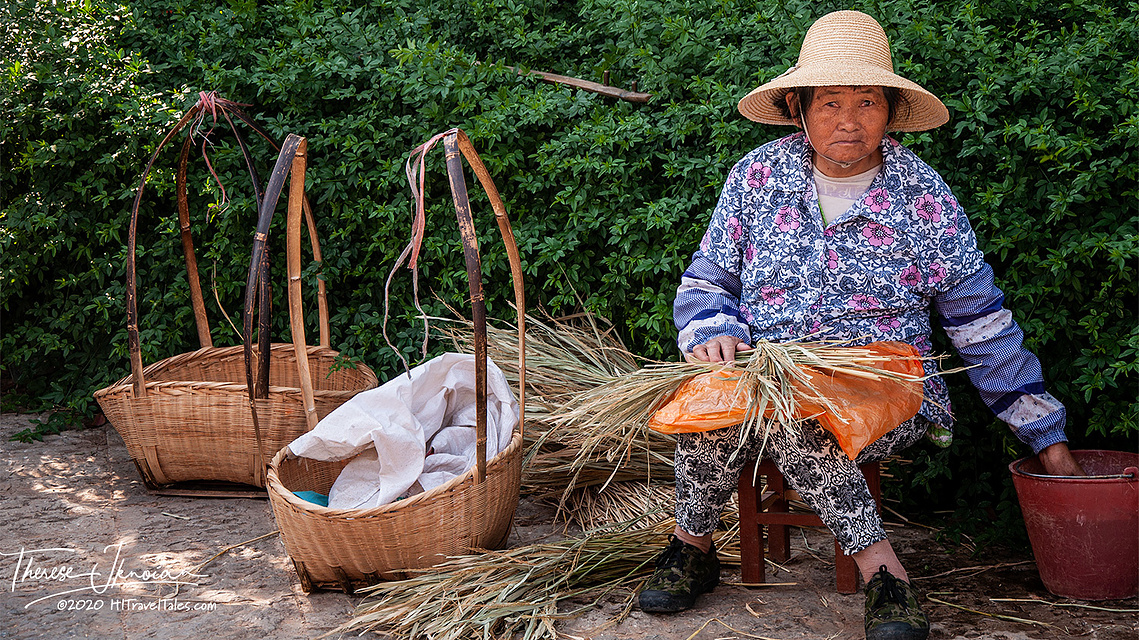 A woman with baskets and dry grasses in Kunming, China. 
