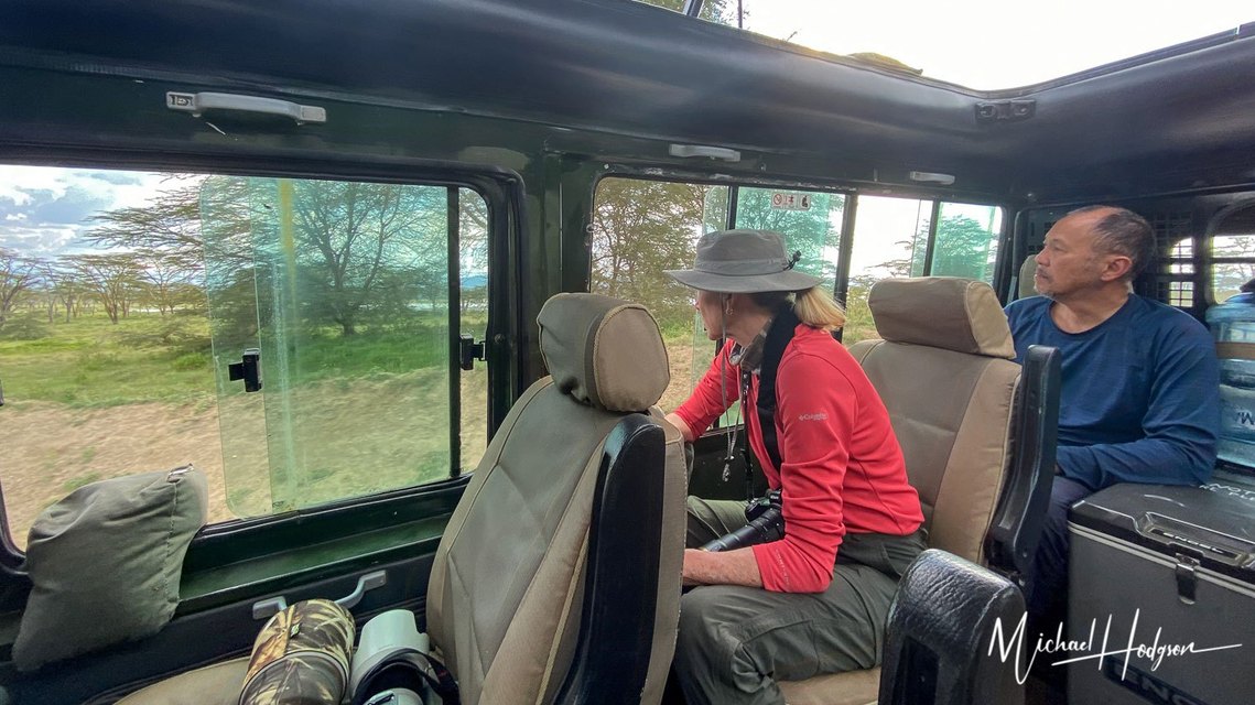 Two photo safari photographers sitting inside a safari vehicle while looking for wildlife to photograph.