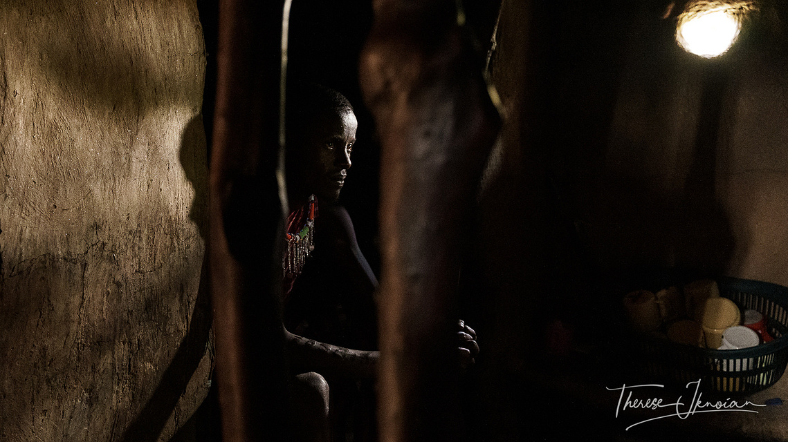 Photo of a Maasai warrior sitting inside his hut in a Maasai village. 