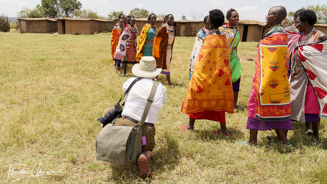 Photo of Michael Hodgson taking photos of Maasai women performing a dance in a Maasai village in Kenya. 