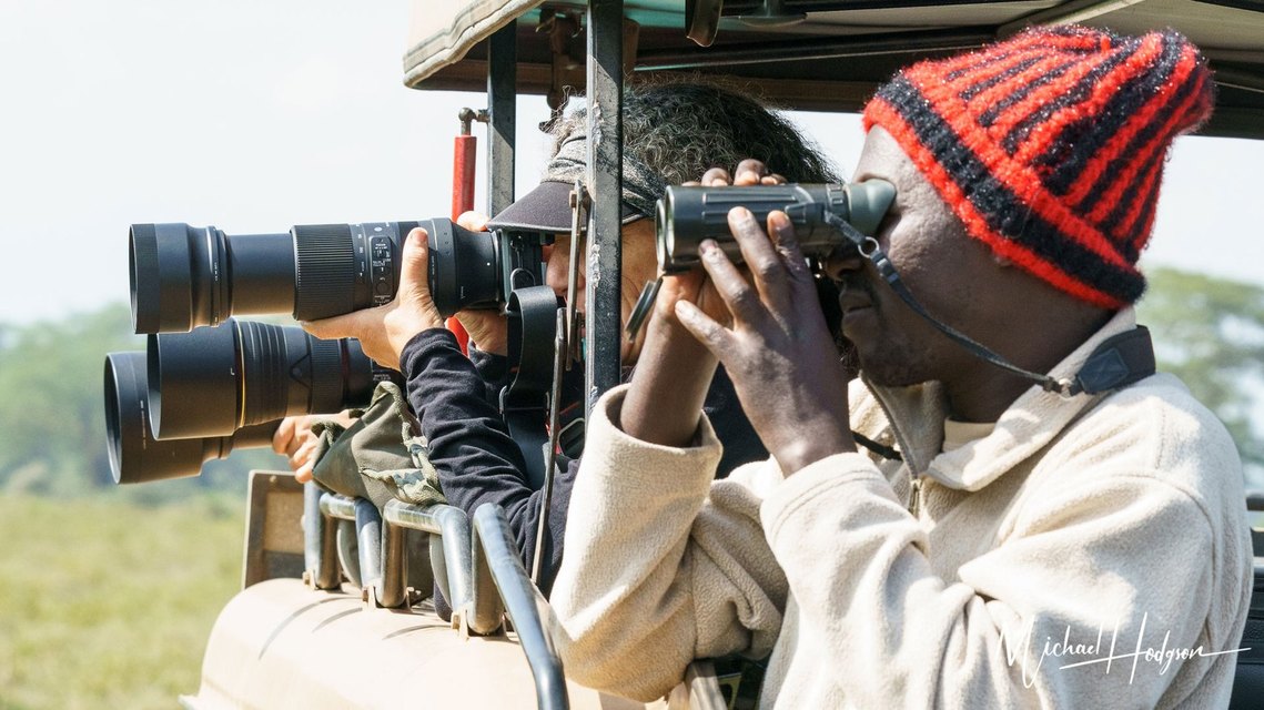 Safari guide and photographers looking at wild animals on a photo safari in Kenya. 