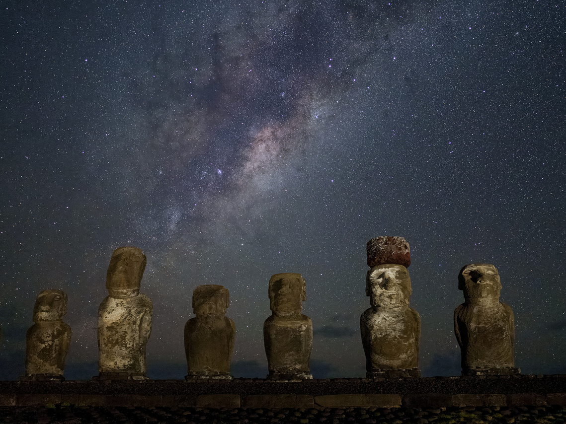 A night photo of a line of famous moai on Easter Island with the Milky Way overhead. 