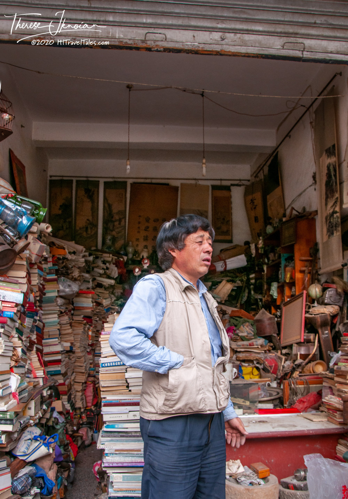 A bookstore owner standing in front of a crazy pile of books in Kunming, China. 