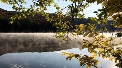 Fog rolls over a lake on an autumn dawn in the Catskills.