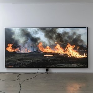 Ausstellungszene mit ​brennenden Ölfeldern im Fernsehen