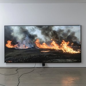 Ausstellungszene mit ​brennenden Ölfeldern im Fernsehen