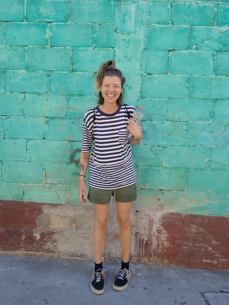 Artist Mary Naylor smiling against a green wall in Puerto Escondida, Mexico 2023