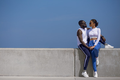Portraits of a couple cuddling outdoors sitting on a concrete wall