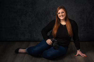 Branding photos of a lady sitting on the studio floor and carrying a camera