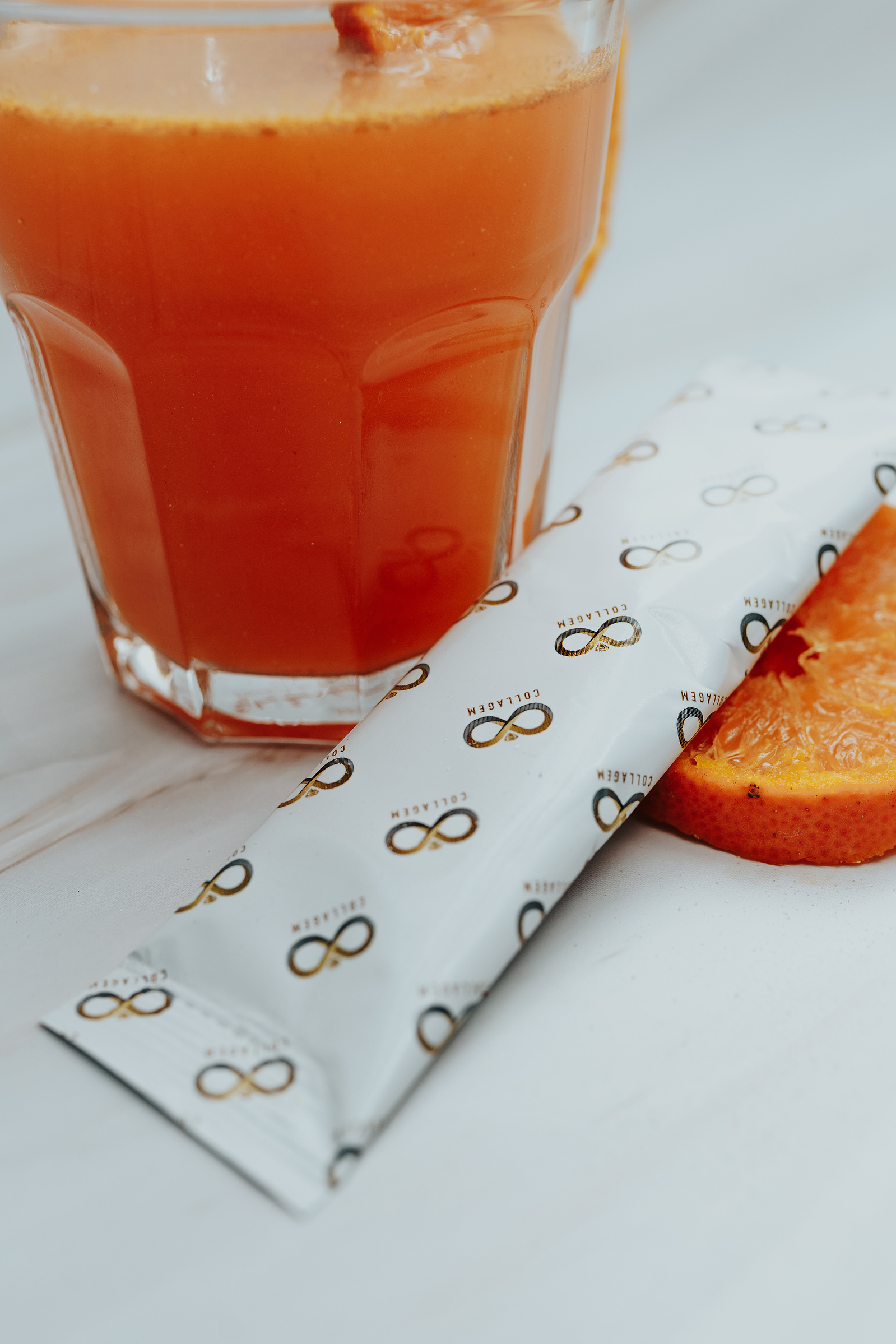 Product photography. Collagem sachet in a glass of water. Sliced nectarines decorate the image.