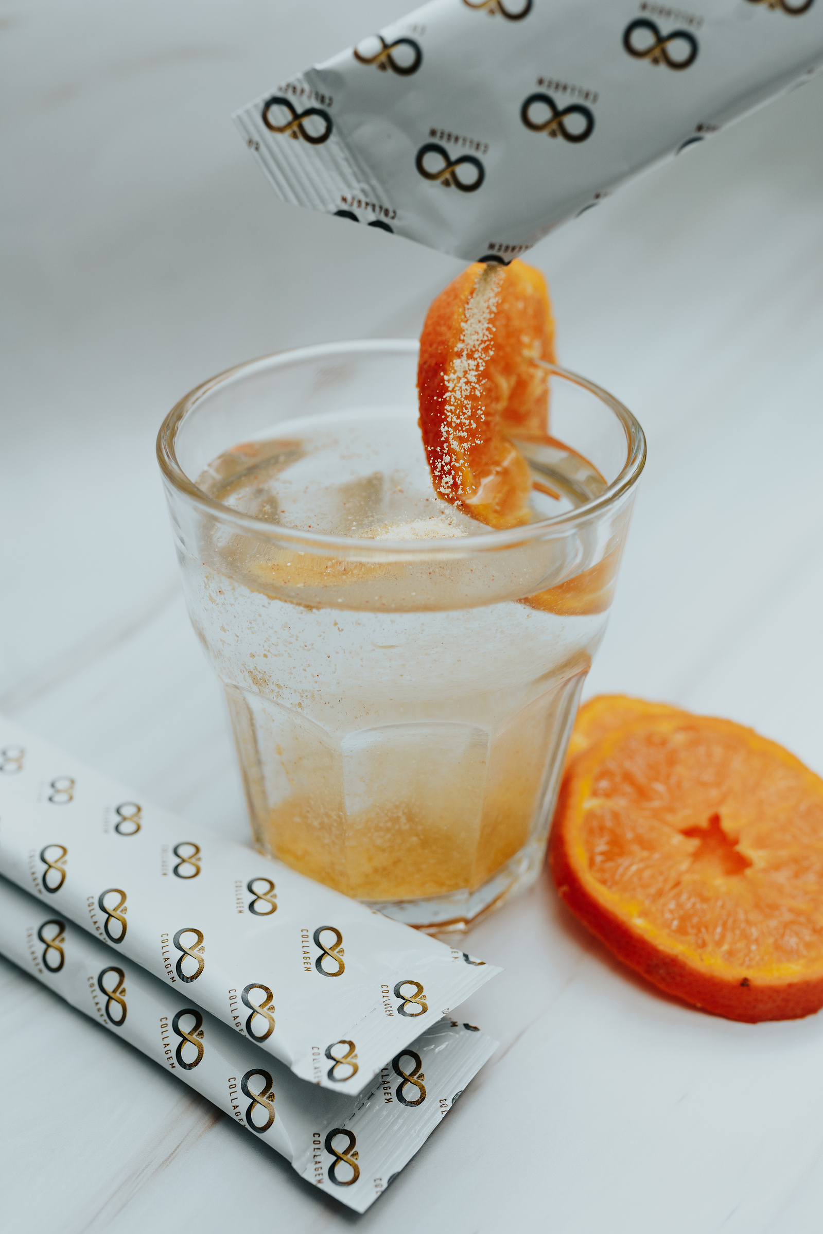 Product photography. Collagem sachet being poured into a glass of water. Sliced nectarines decorate the image.