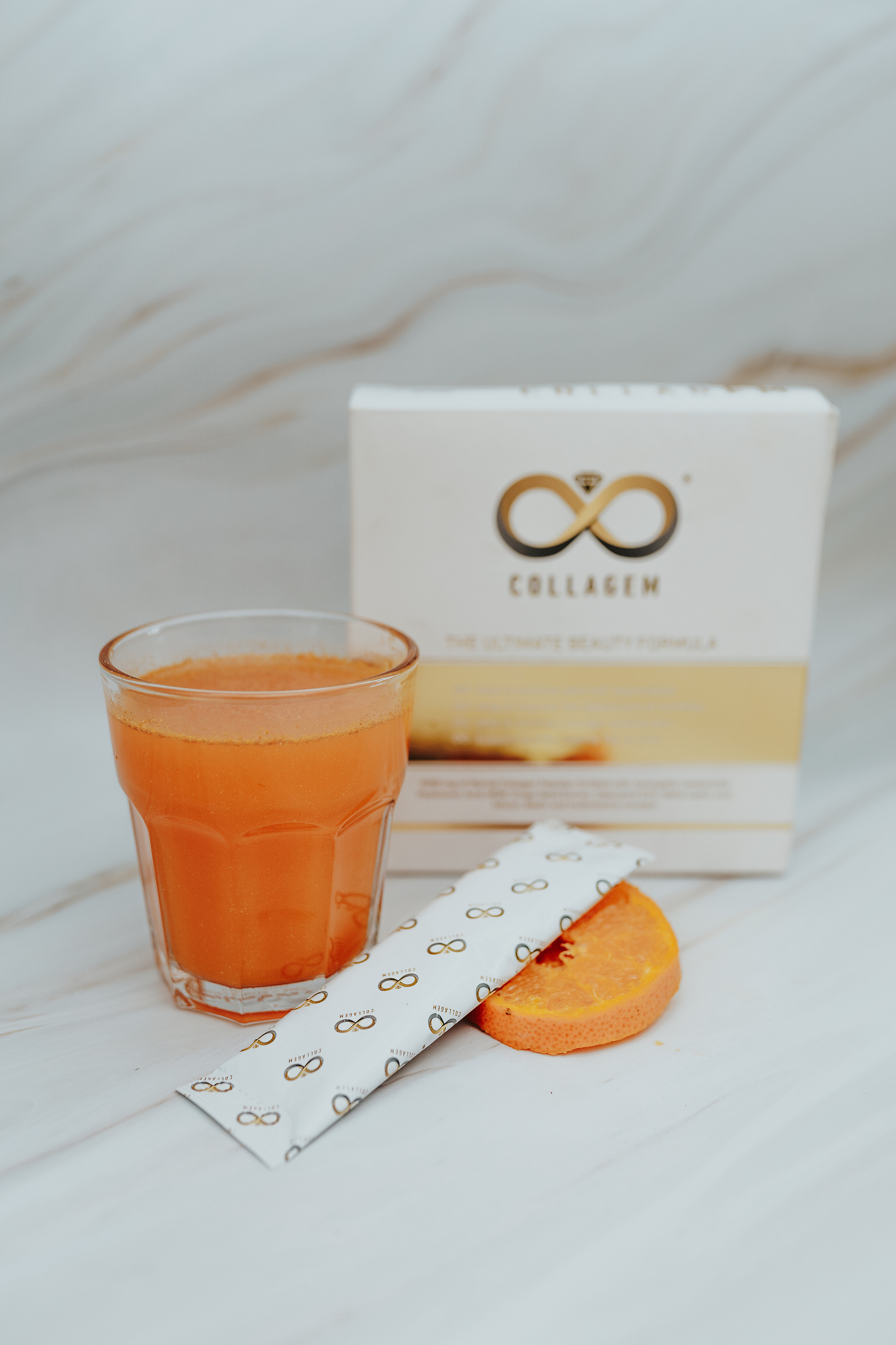 Product photography. Collagem sachet in a glass of water. Sliced nectarines and the Collagem box decorate the image.