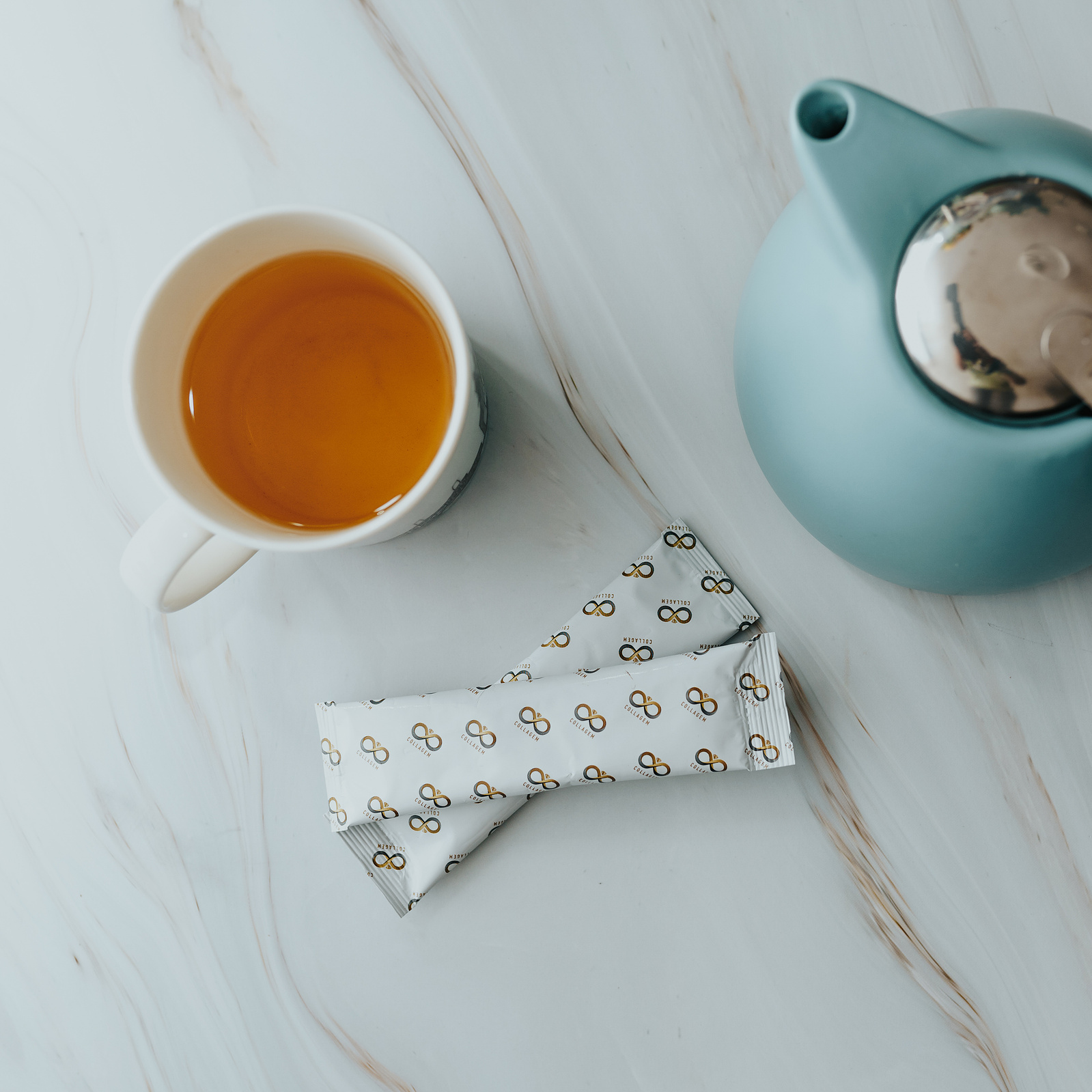 Product photography. Collagem sachet amongst a mug of tea and a tea kettle.