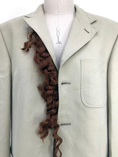Integrating hair with garments. Fake curly red hair on the placket of beige men's jacket.