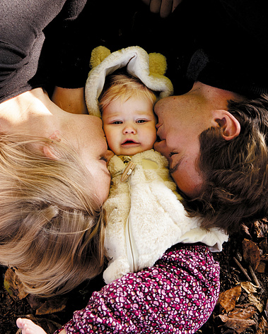 Family photography. A young couple have their portrait taken with their baby daughter and  express their appreciation and thanks.