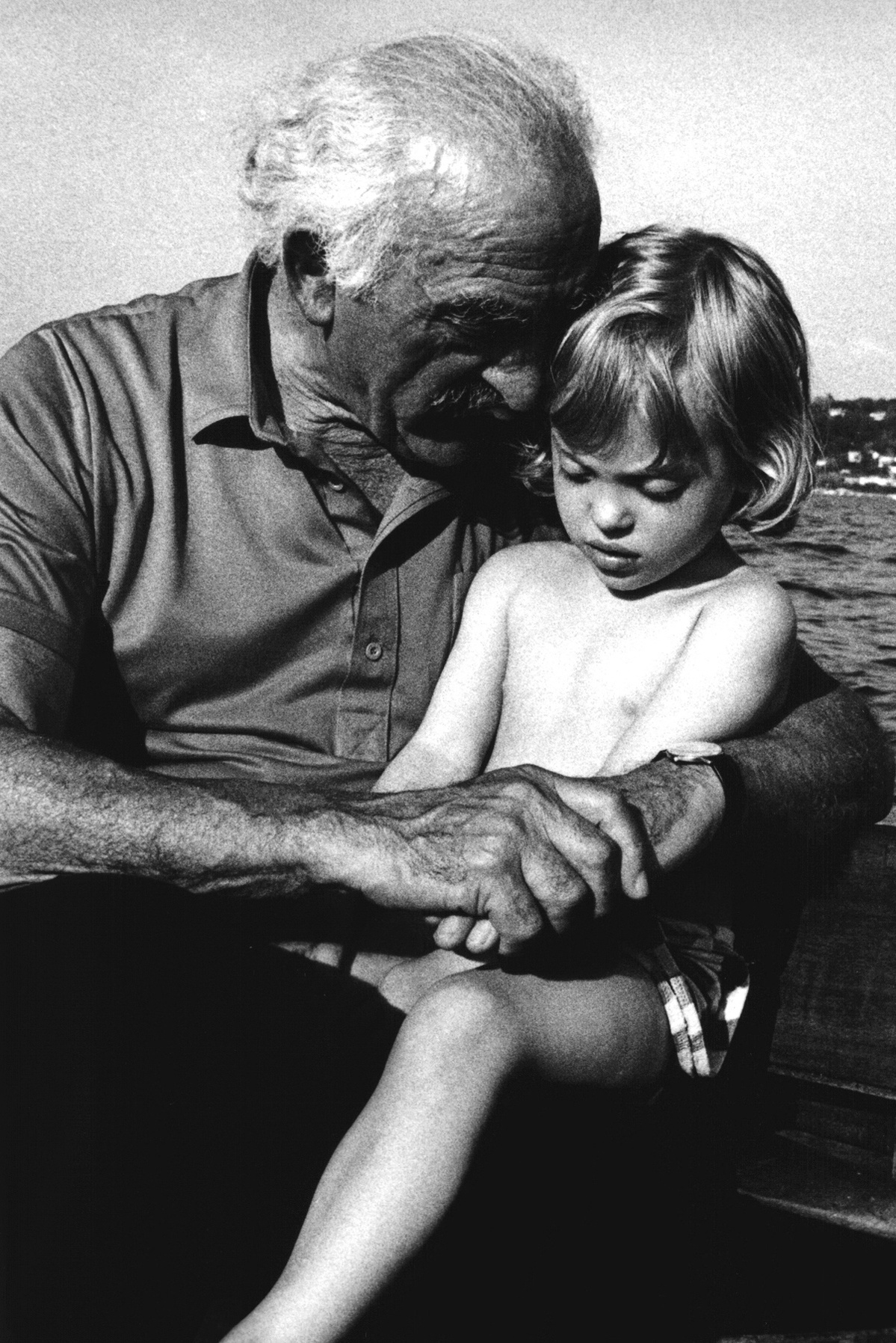 Family photographer Geneva. Portrait of my late father, telling a story to Anaïs, my eldest daughter on lake Geneva. This was taken on an vintage wooden sailing boat called Fly.