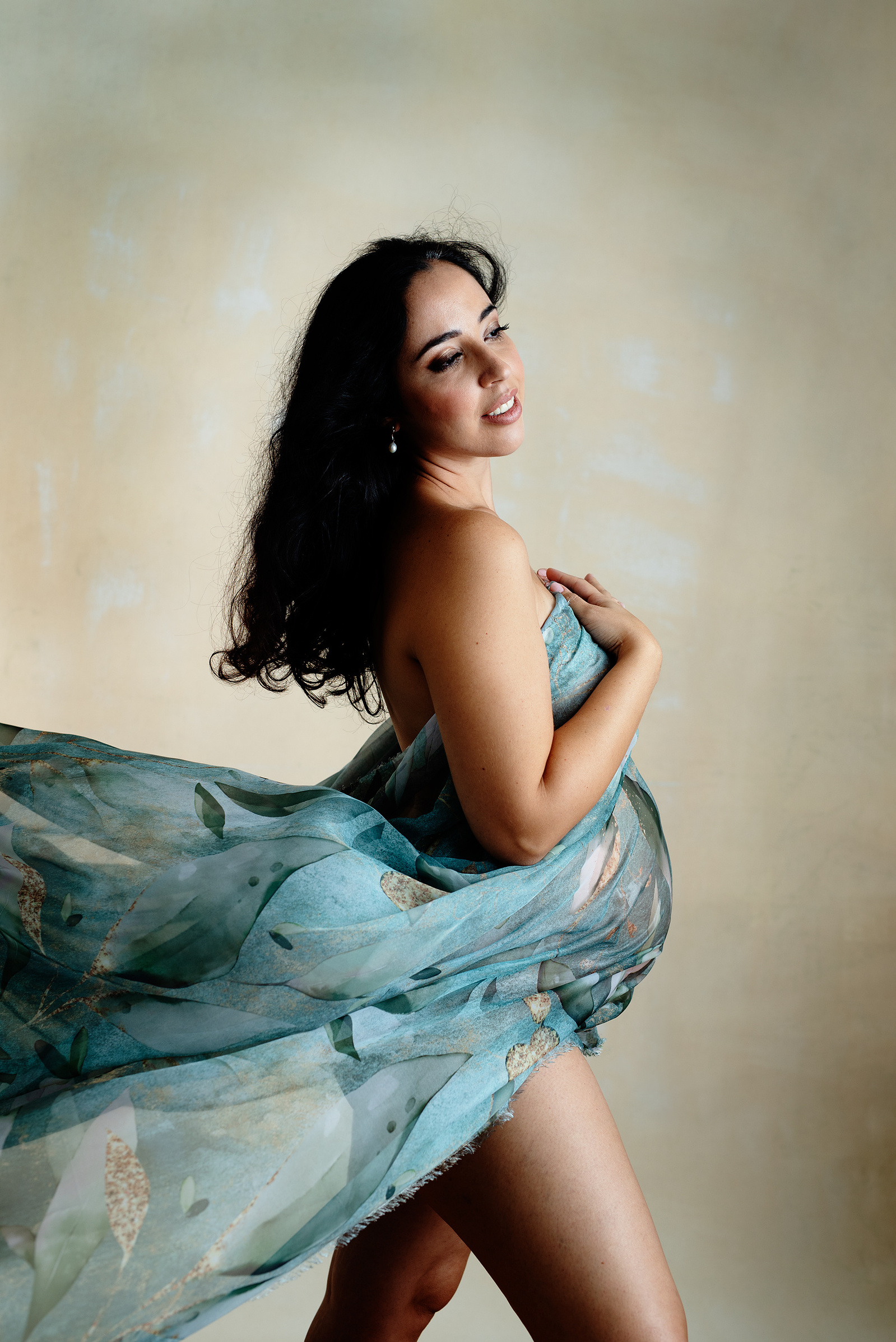 Fine-Art Maternity photographer based in Chêne-Bougeries, Geneva. Beautiful blue-green material is draped around her pregnant belly and blown behind her.