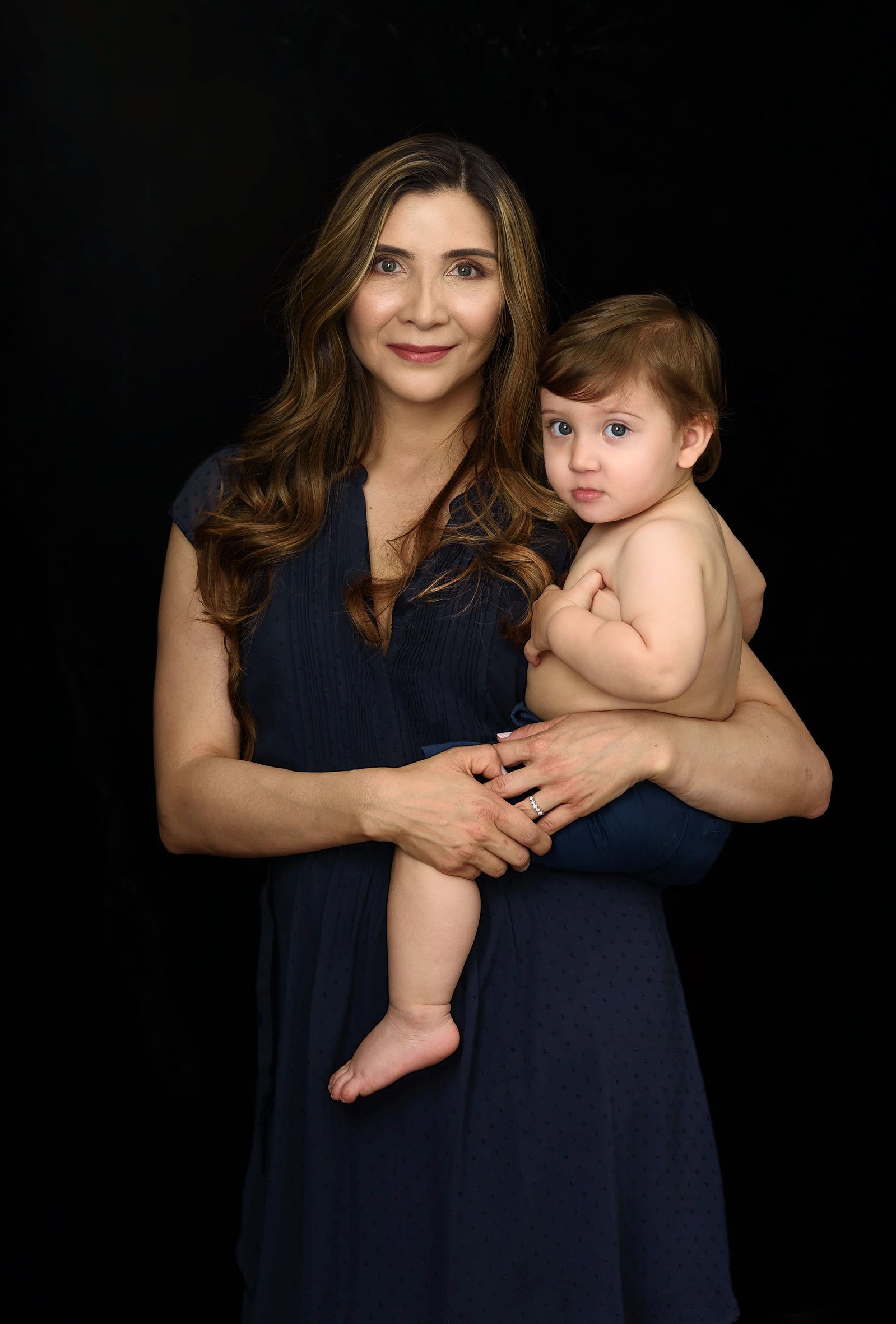 Fine-art Mummy and Me portrait. Mother photographed with her son on a black velvet background on the occasion of Mother's Day. We created heirloom portraits as Wall Art to remind the family everyday of their love for each other.