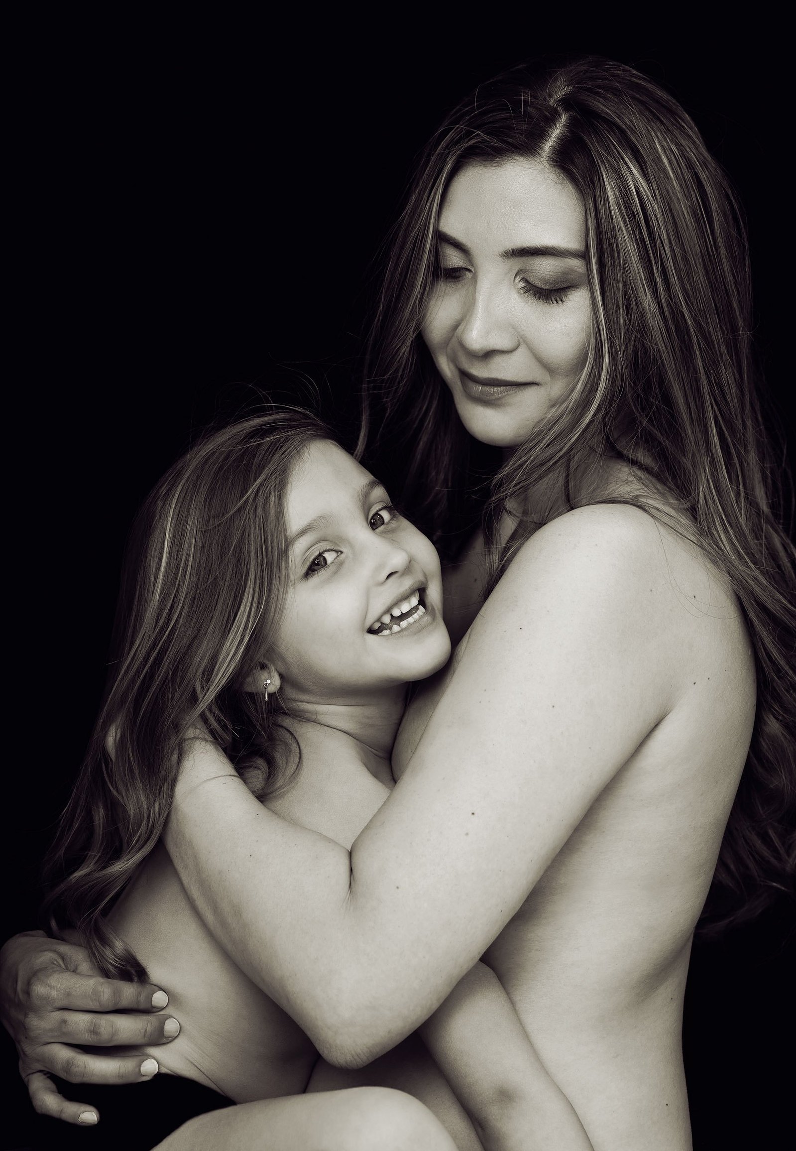 Fine-art Mummy and Me portrait. Mother photographed in black and white with her daughter, sitting close, smiling, their hair blending. We created these heirloom portraits as Wall Art to remind the family for years to come of their love for each other.