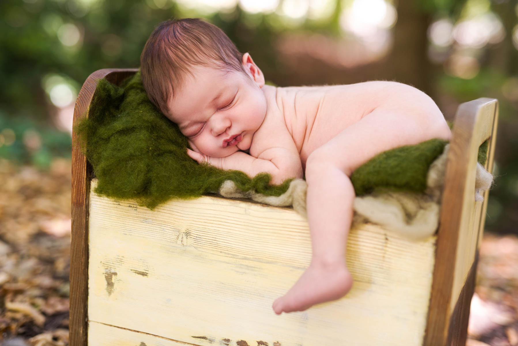 Colour photograph of a newborn baby boy sleeping soundly on my home-made wooden bed on a green felt blanket beside the river Seymaz, Chene-Bougeries.
Family Newborn photographer.