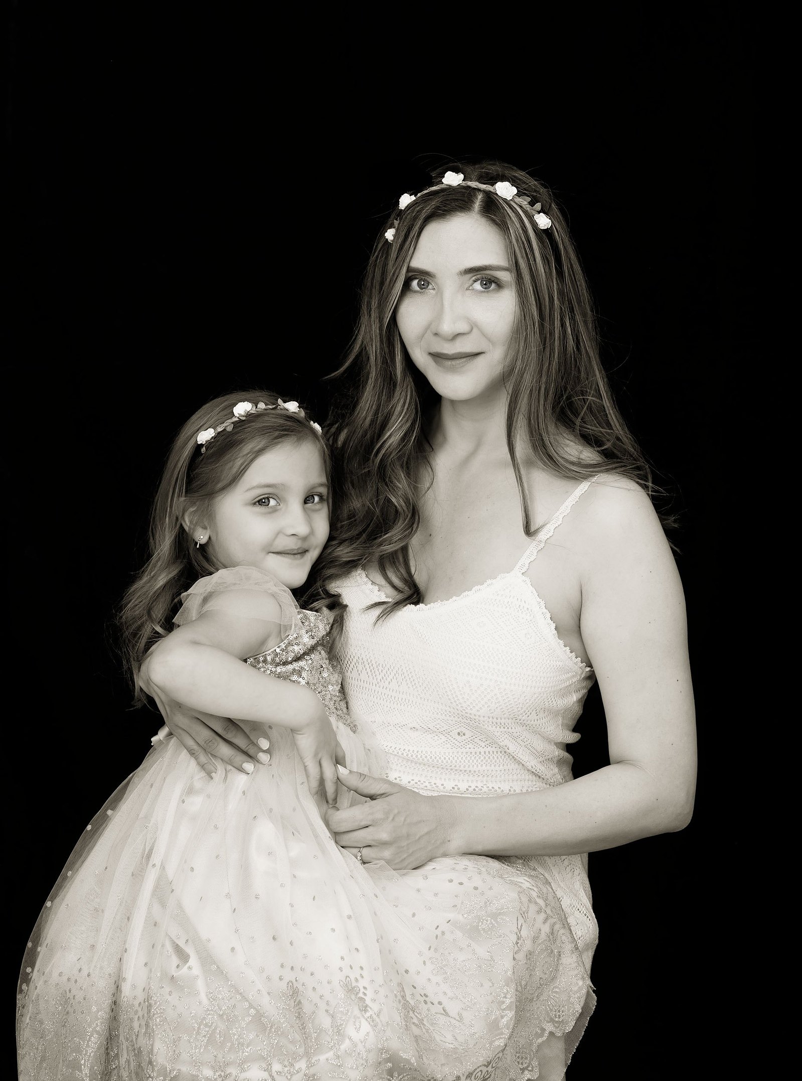 Black and white Mummy and Me portrait. Mother photographed with her daughter, both wearing cream dresses and flowered headbands. We created Mummy and Me portraits to treasure as Wall Art to remind the family everyday of their love for each other.