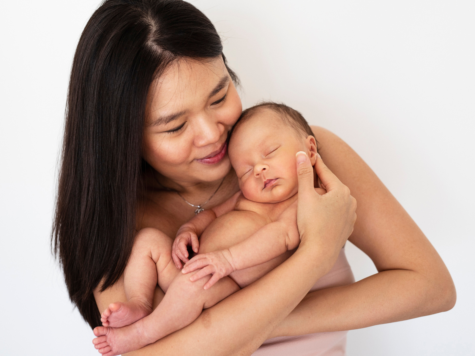 Mother cradles her newborn baby son in her arms for a photographic portrait which she will cherish for many many years. Photographed by Geneva's leading family and newborn photographer, Helen Putsman who is based in Chêne-Bougeries.