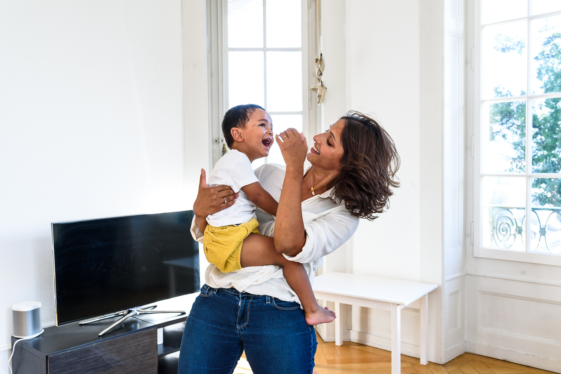 Portrait of mum with her young son in her arms, playing with him. Taken during a lifestyle family portrait photo session shot in Geneva.