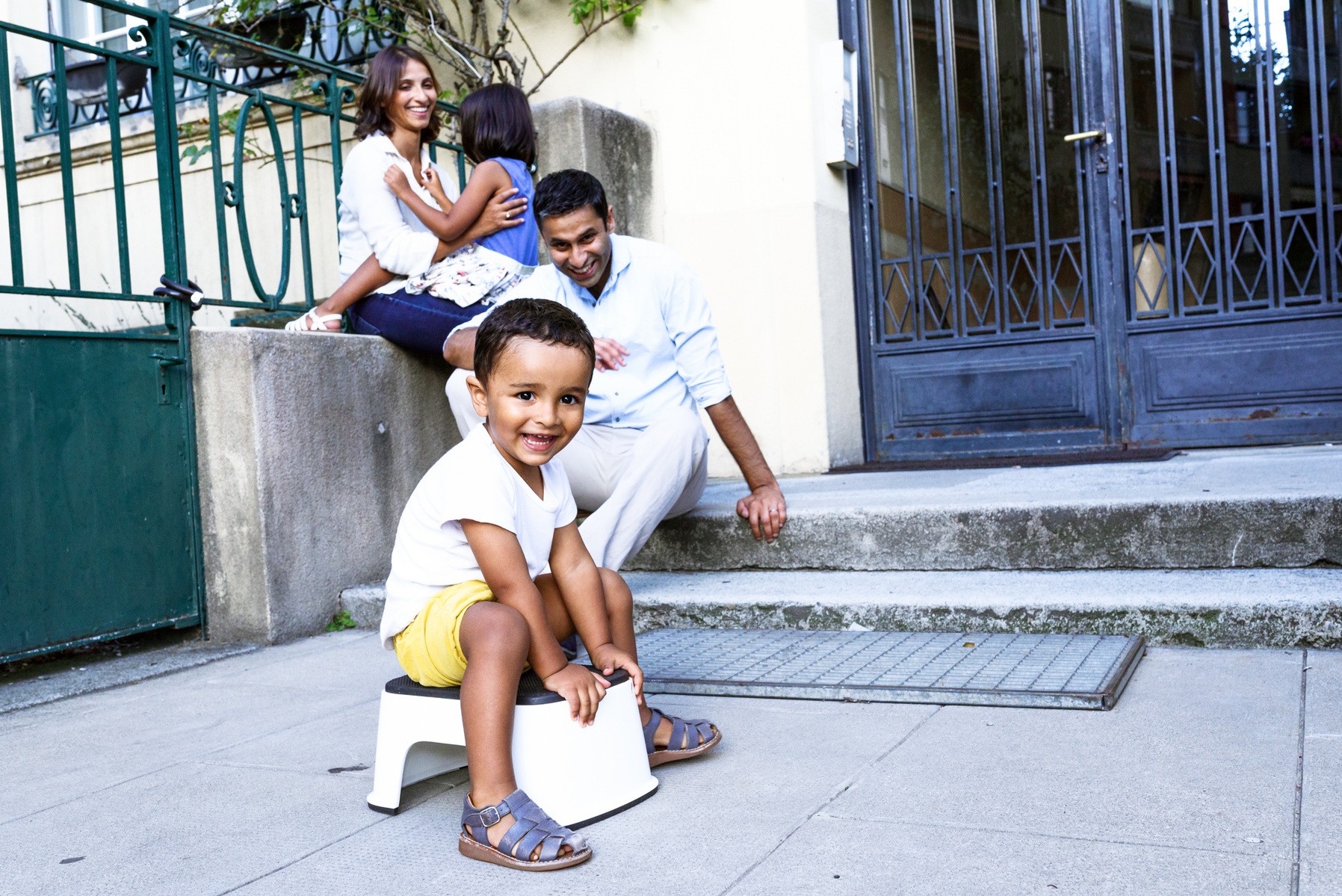 Reportage photo of the youngest of the family playing with the rest of the family in the background. Shot in Geneva, Switzerland.