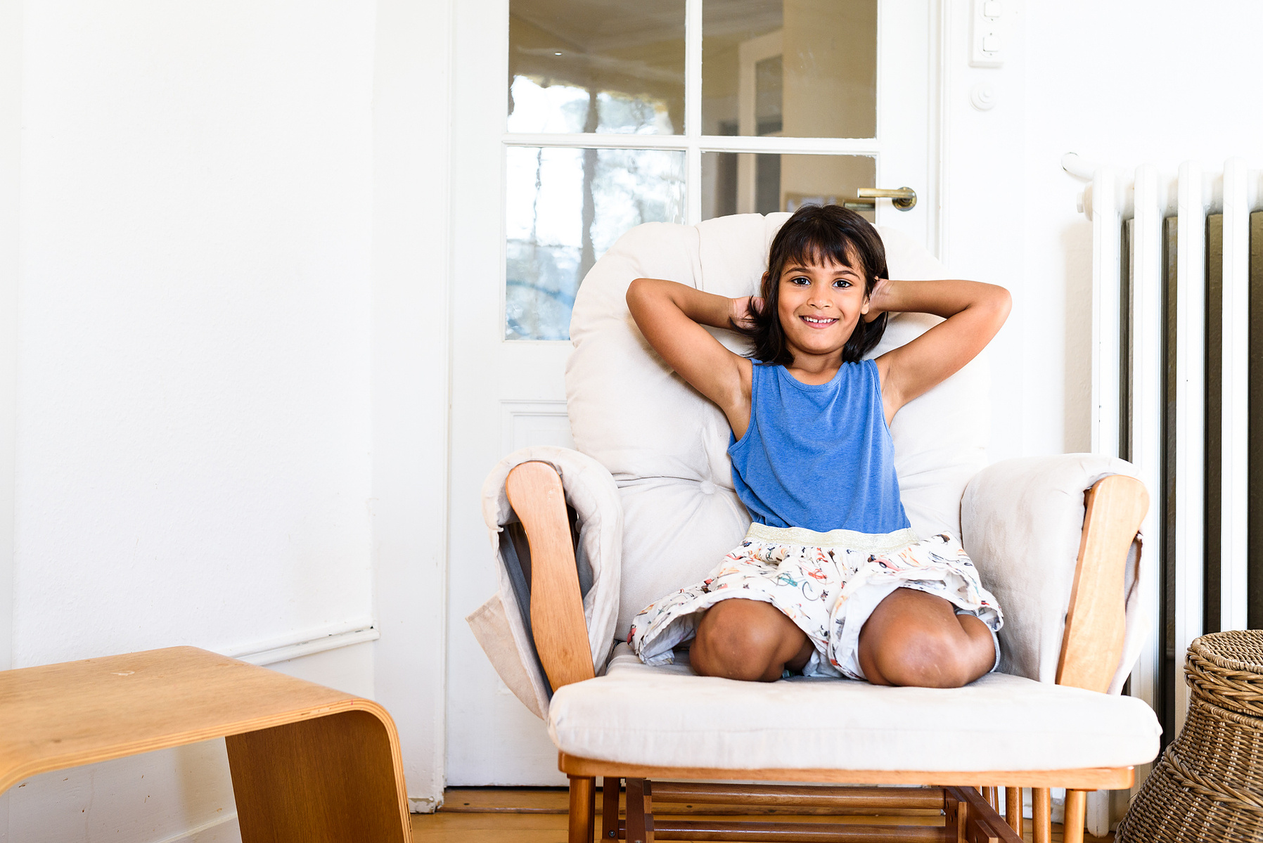 Portrait taken of a girl seated in her family armchair taken during a lifestyle family photo-shoot shot in Geneva.