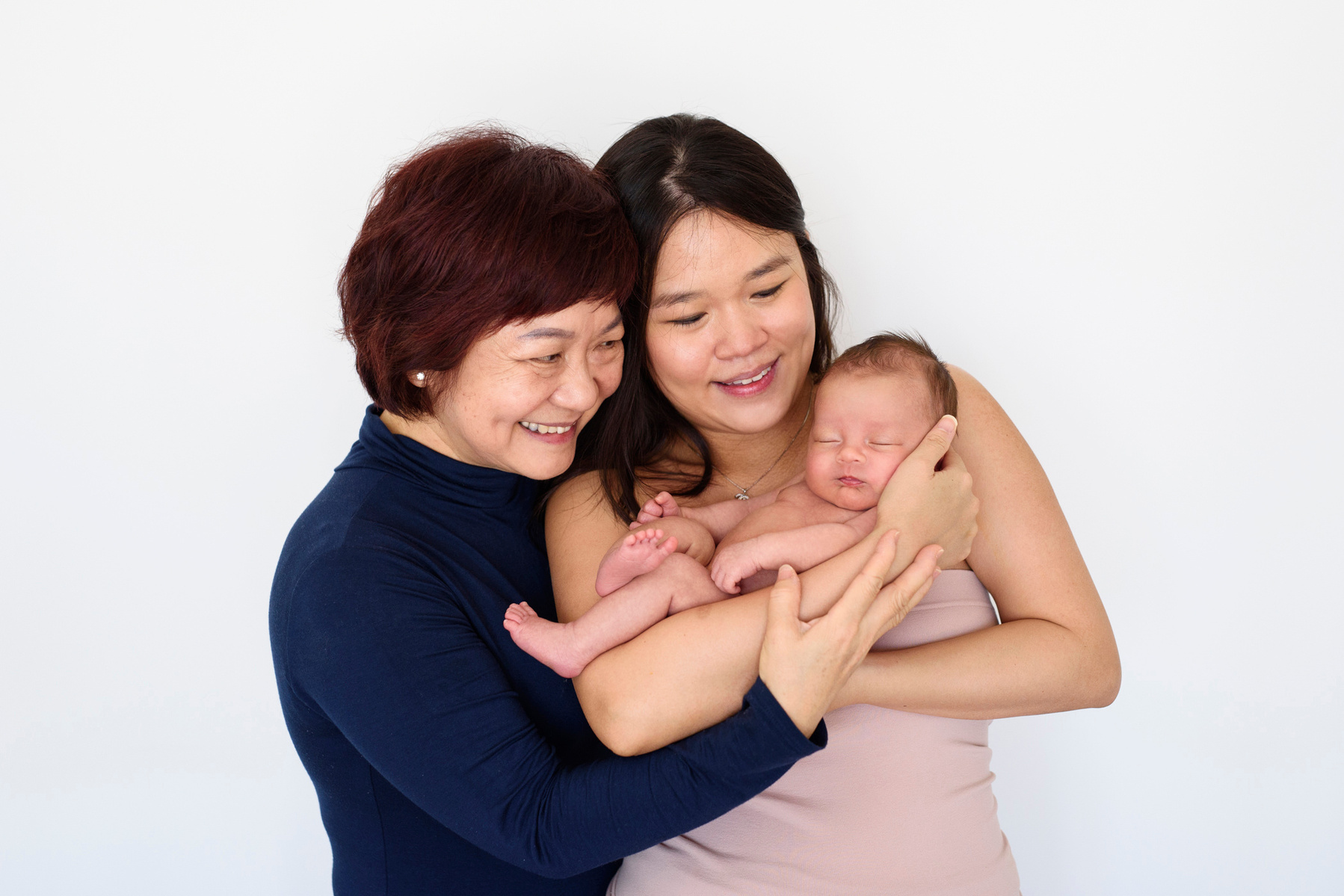 Three generations, the mother cradles her newborn son in her arms whilst the grandmother gets close for a family portrait. Photographed by Geneva's leading portrait photographer, Helen Putsman, based in Chêne-Bougeries.