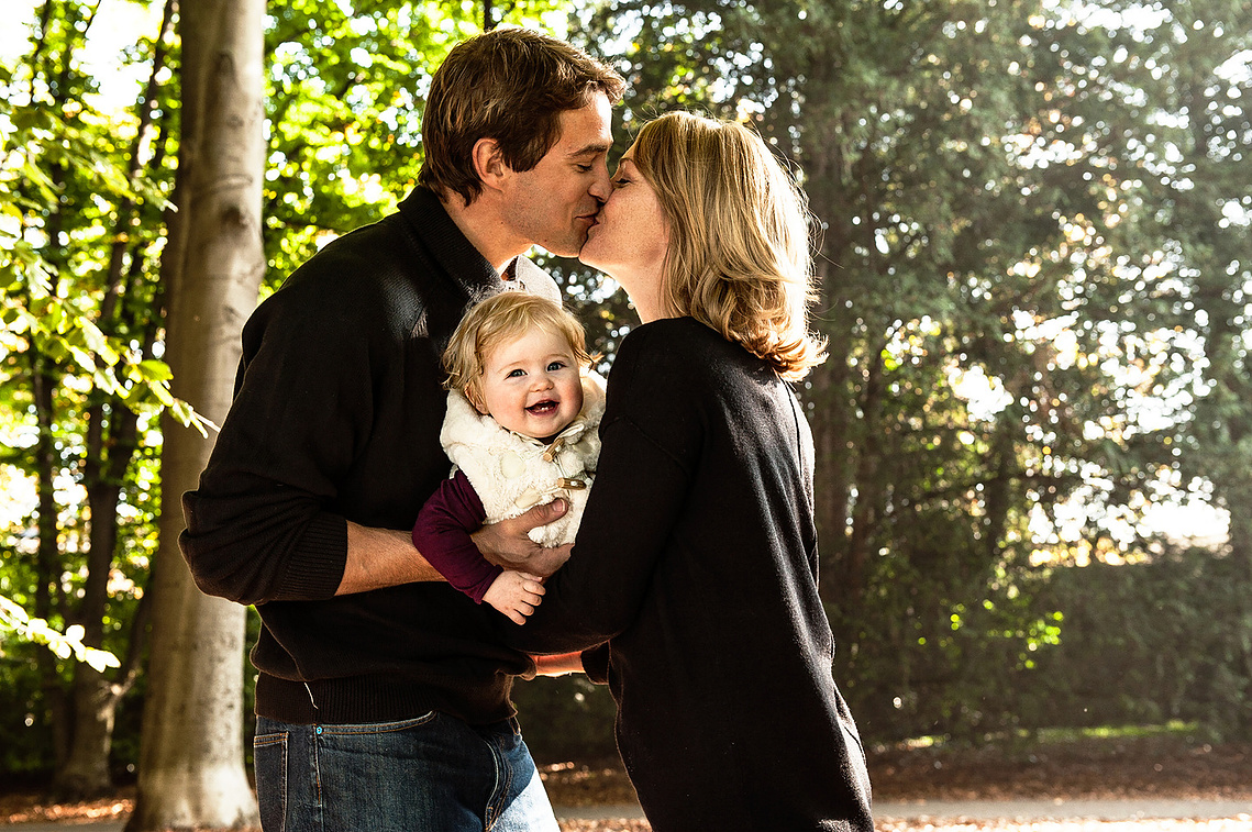 Young parents holding their baby daughter for a beautiful portrait to put on their walls. 30-MINUTE MINI PORTRAIT SESSION · CHF 195 - Up to 3 people · (can include a dog),3 retouched high-resolution digital portraits Preparation guide with wardrobe advice