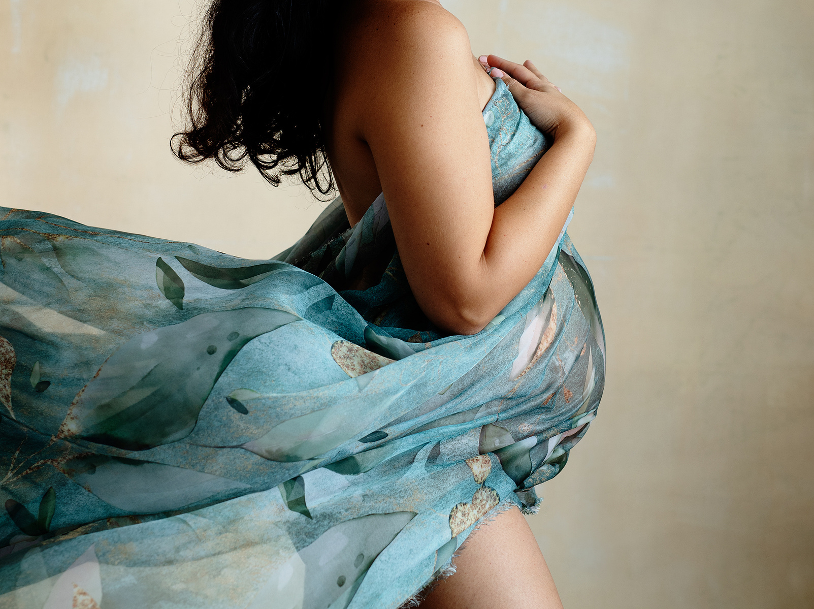 Fine-Art Maternity photographer based in Chêne-Bougeries, Geneva. Beautiful blue-green material is draped around her pregnant belly and blown behind her.